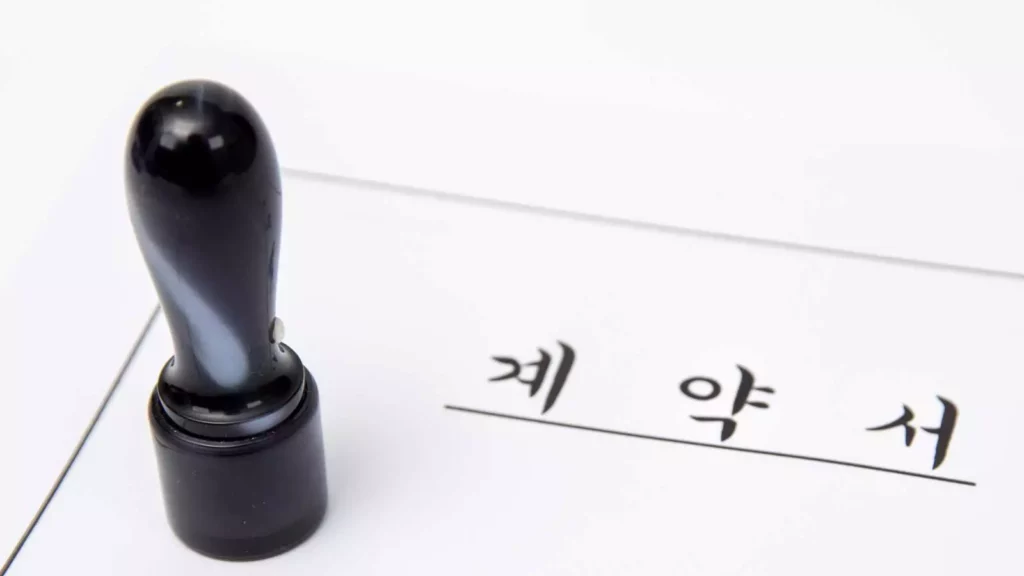법적 효력을 갖는 중요한 계약서 서류 위에 올려져 있는 검은색 계약용 인감도장의 클로즈업 사진